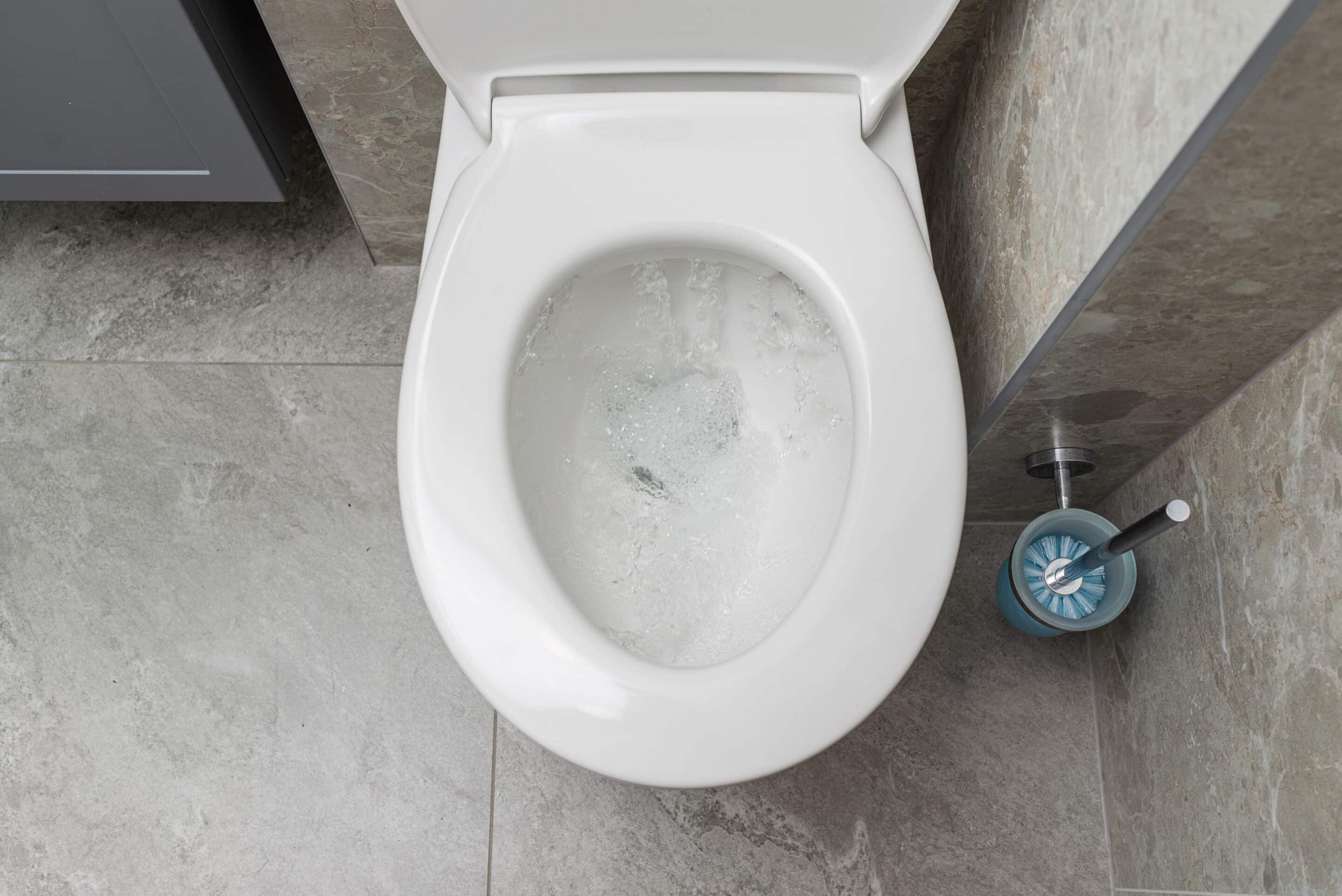 Water is running in the toilet in the bathroom, view from above.